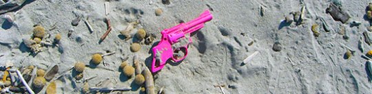 Spielzeugpistole Plastik pink im Sand